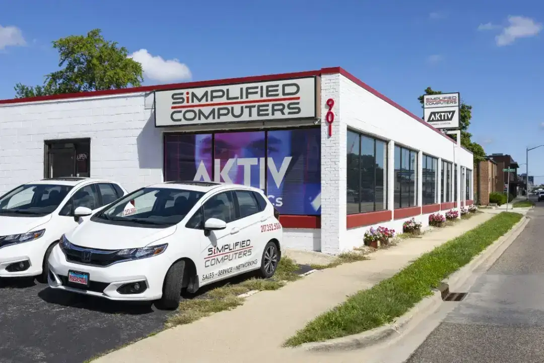 Wide-angle view of the Simplified Computers storefront in Champaign, featuring bold signage, a glass entrance, and parked vehicles out front under a clear sky—representing a trusted location for PC repair in Champaign, expert IT support, and professional computer repair through Simplified Business.