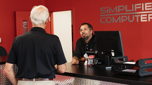 Simplified Computers team assisting a customer at the service counter.